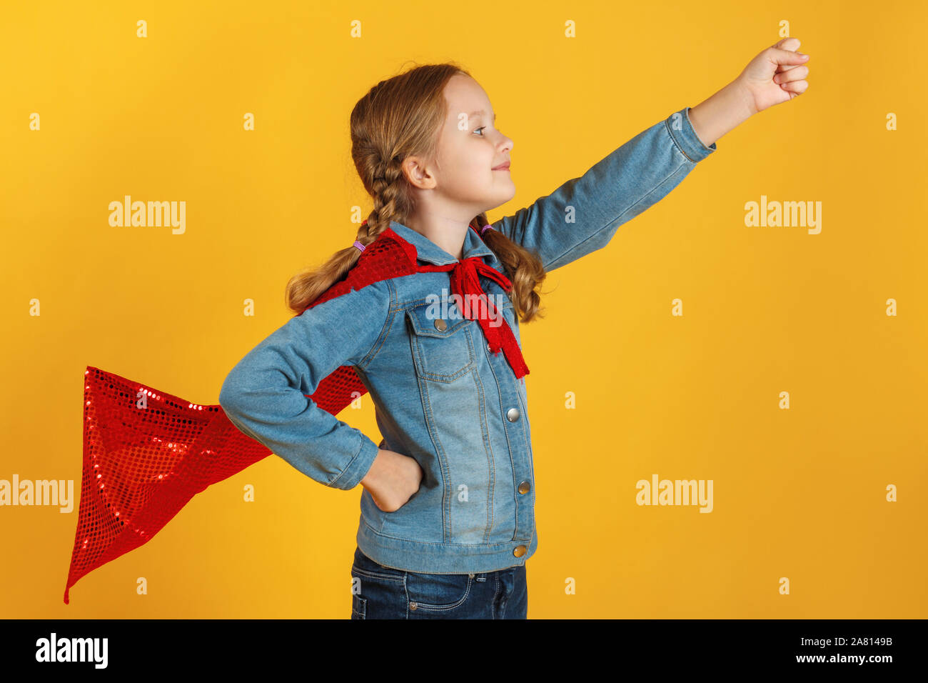 Kleines Mädchen Superhelden auf gelbem Hintergrund. Das Kind hob die Hand. Girl Power Konzept. Stockfoto