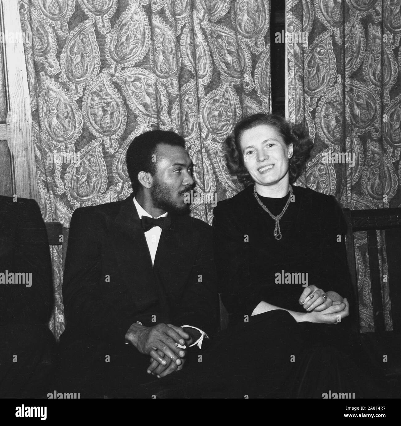 1950er Jahre, historisches, post-wat Großbritannien und eine elegante englische Dame bei einem Black-Tie-Tanz neben einem afrikanischen Besucher aus Übersee, London, England, Großbritannien. In dieser Ära kamen viele Völker aus den überseeischen Commonwealth-Ländern nach Großbritannien, um zu arbeiten und zu studieren, und es fanden kulturelle Austauschmaßnahmen und Tänze statt, um sie in die britische Lebensweise einzuführen. Stockfoto