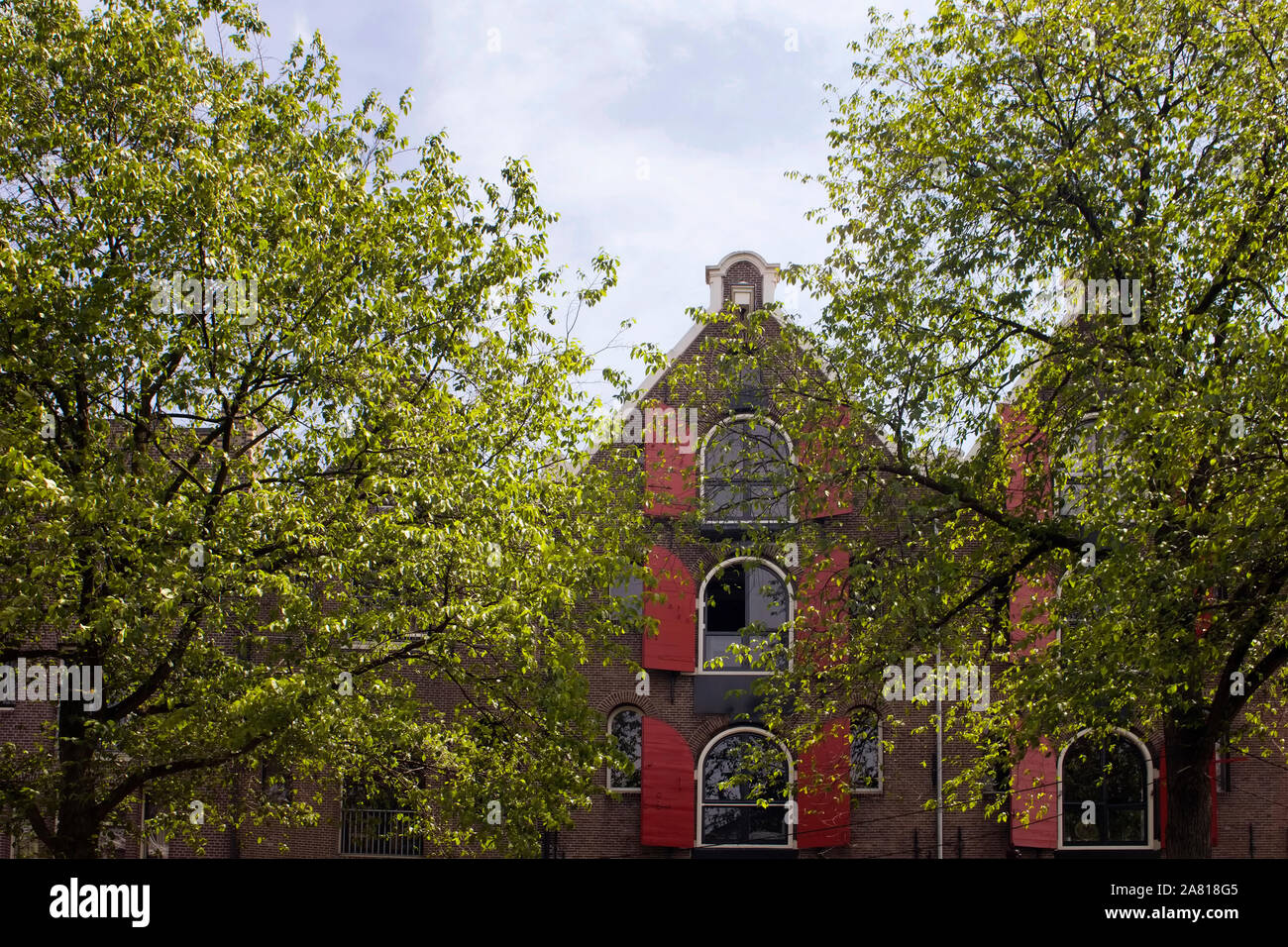 Blick auf die historische, traditionelle und typische Gebäude zeigen Niederländische architektonischen Stil und Bäume in Amsterdam. Es ist ein sonniger Sommertag. Stockfoto