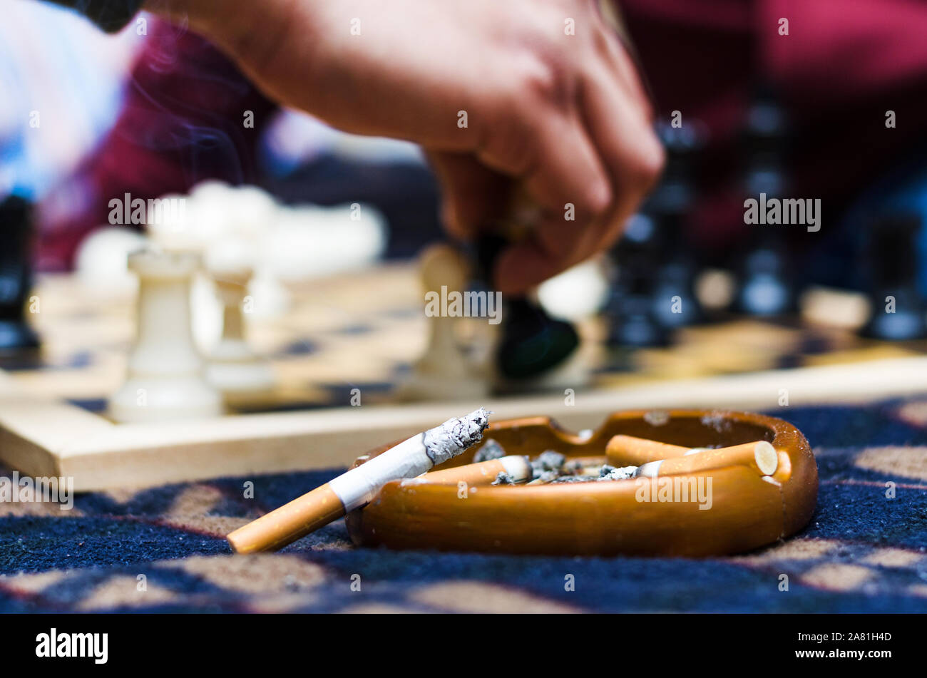 Zigarre auf einen Aschenbecher mit dem Hintergrund einer Partie Schach Stockfoto