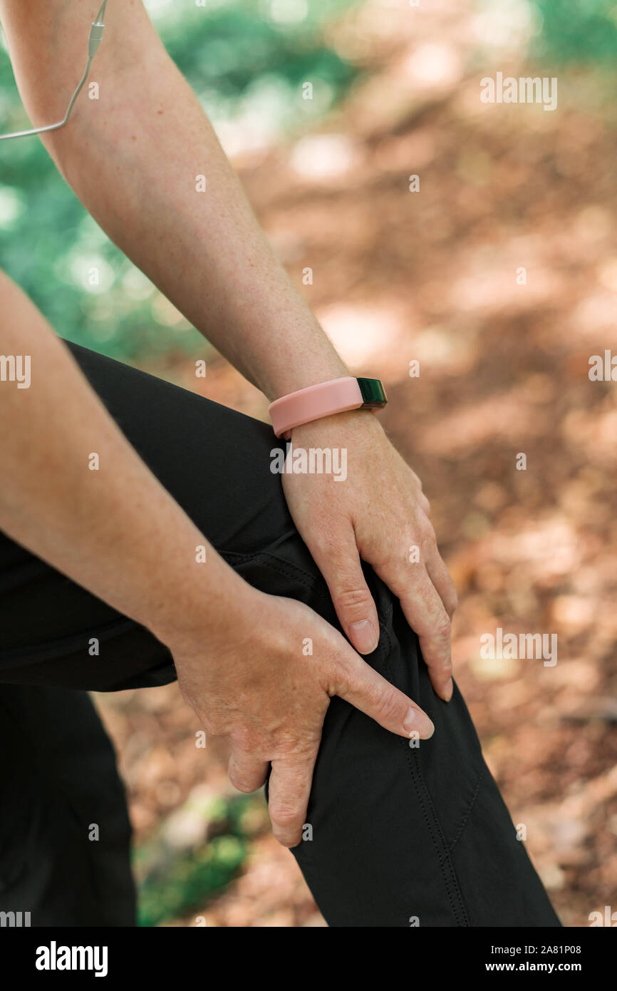 Weibliche Wanderer mit Knieverletzung in Wald bei Outdoor trekking Aktivität, selektiver Fokus Stockfoto