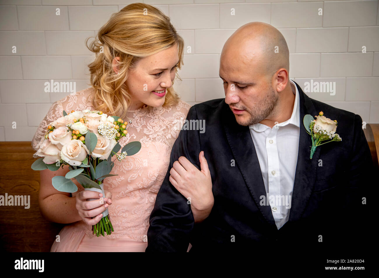 Nahaufnahme von Braut und Bräutigam in Vintage Kleidung sitzen und berühren sich und die Braut holding Blumenstrauß warten zu heiraten Stockfoto