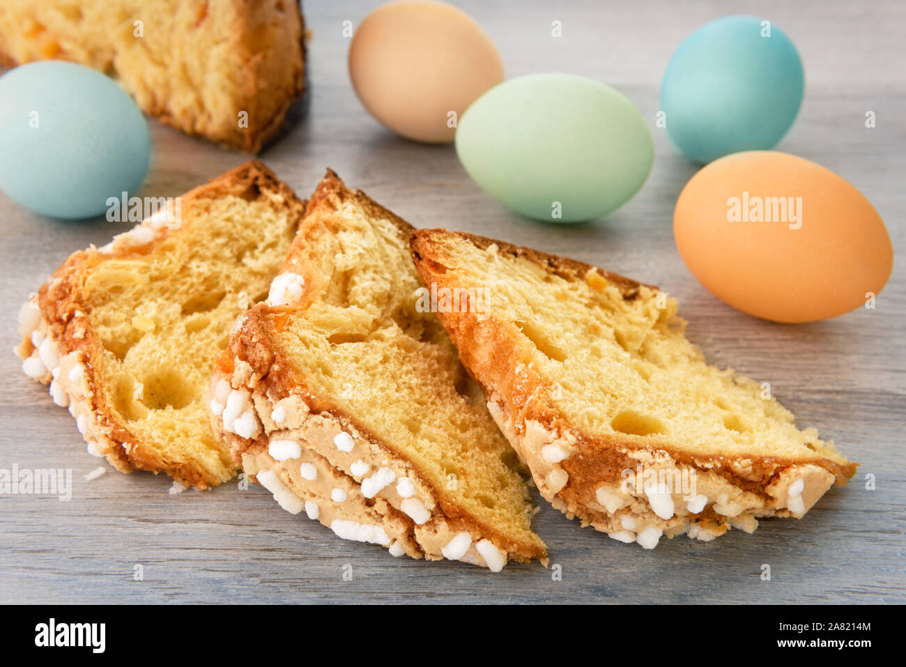 Scheiben von Ostern Kuchen und bunte Eier werden auf einem hölzernen Tisch. Stockfoto