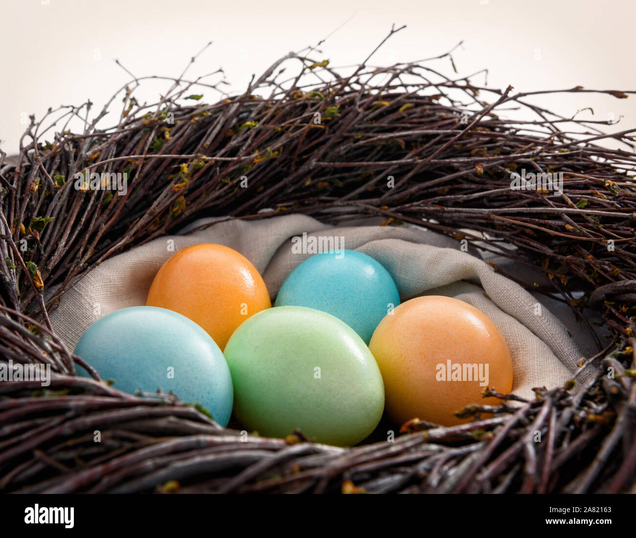 Ostern noch leben. Bunte eier in ein Nest auf einer hölzernen Oberfläche. Stockfoto