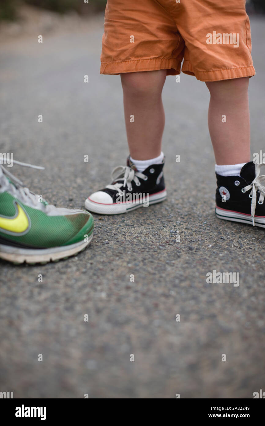 Schuhe für Kleinkinder stehen auf Zement Straße und Erwachsenen. Stockfoto