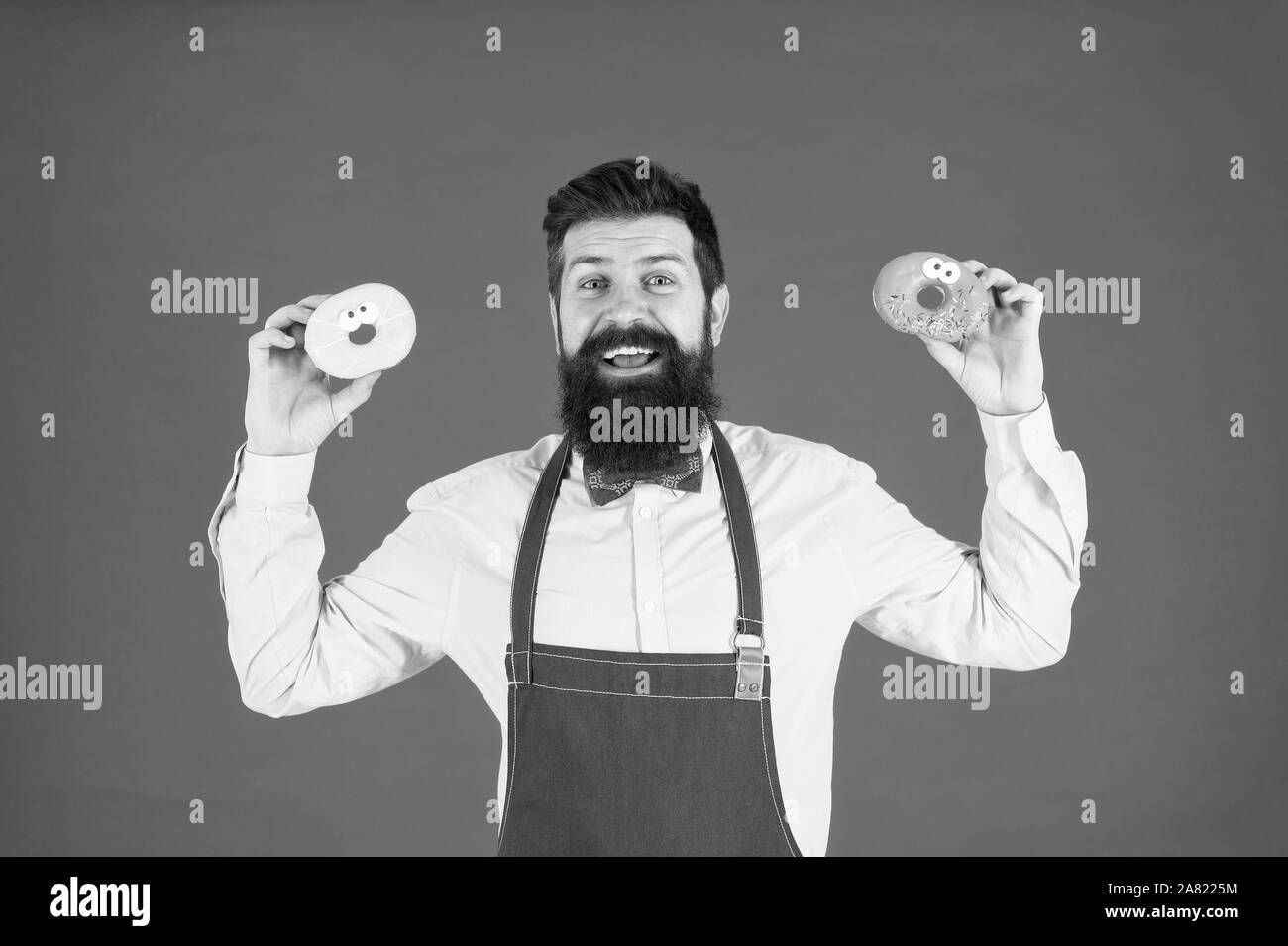 Sharing lustig Donuts. Der bärtige Mann mit Ring Donuts auf roten Hintergrund. Professionelle Bäcker mit leckerem glasierte Krapfen. Hipster mit gebratenen Donuts in den Händen. Stockfoto