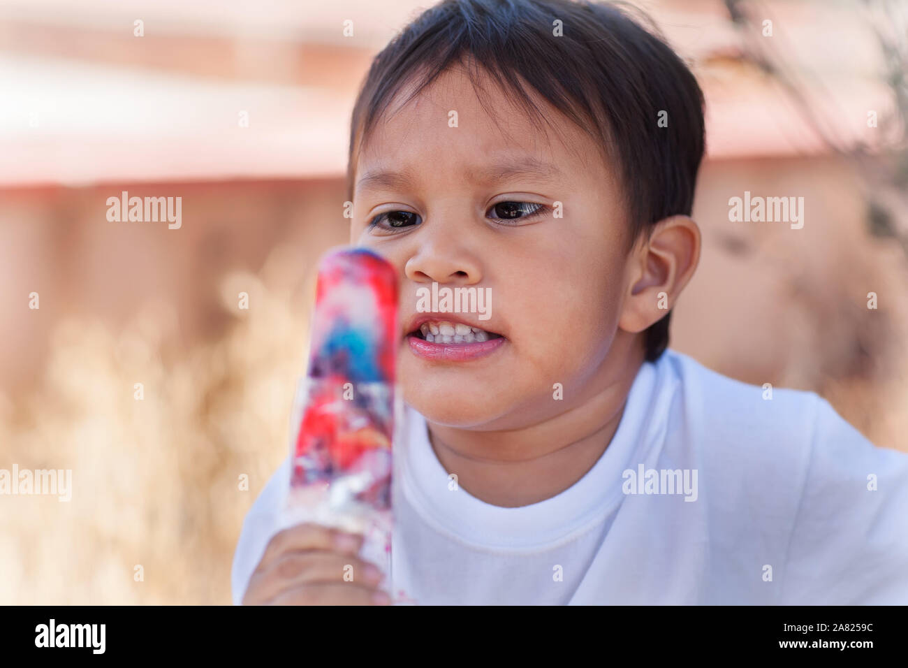 Ein Hispanic kleines Kind bereit, einen bunten Ice pop zu Essen bekommen. Stockfoto