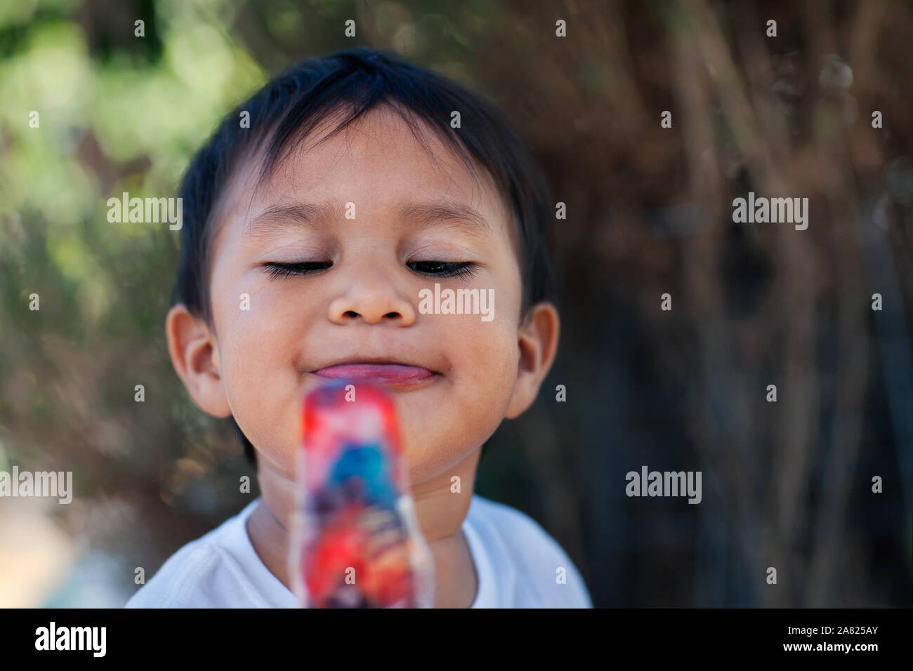 Ein Junge mit einem gefrorenem Eis pop Behandeln mit einem großen Lächeln auf seinem Gesicht. Stockfoto