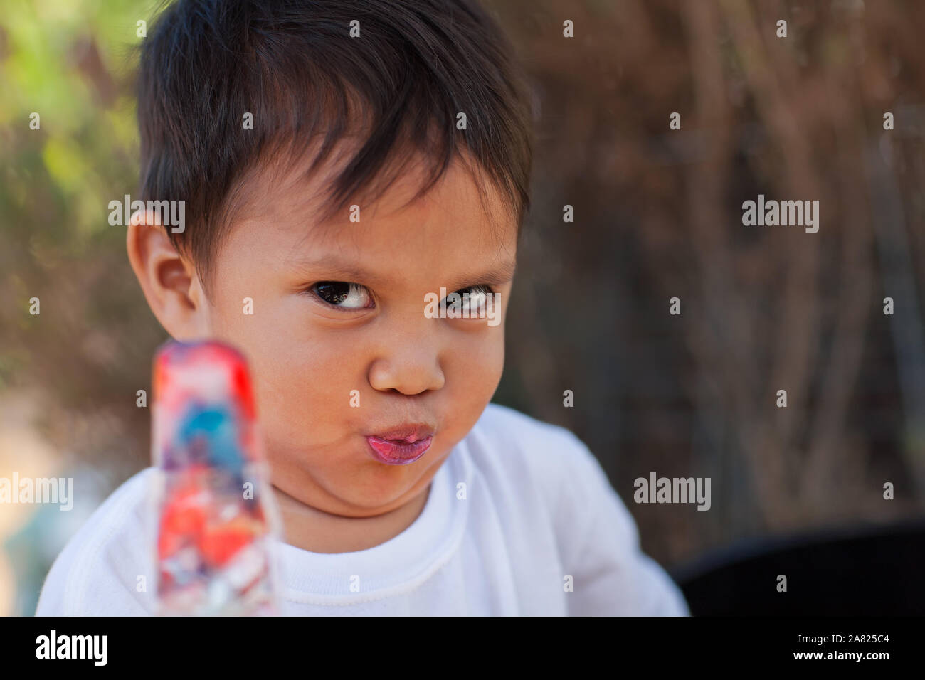 Ein kleiner Junge einen lustigen Gesichtsausdruck nach der Verkostung ein Eis pop behandeln und finden es zu sauer. Stockfoto