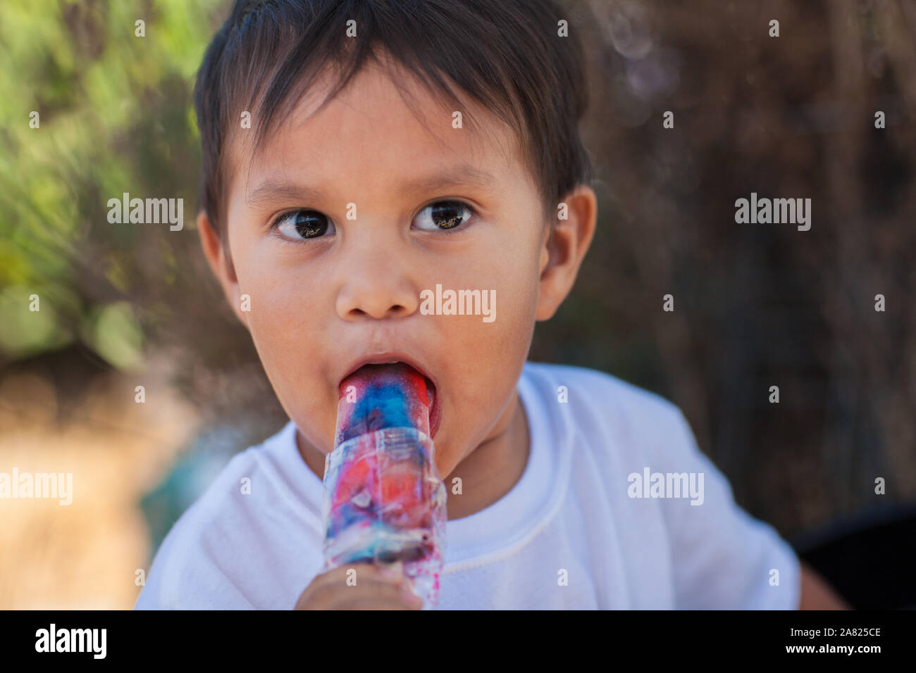 Einen jungen Latino boy Essen eine gefrorene Eis behandeln und mit einem Blick der Überraschung in seinem Gesicht. Stockfoto