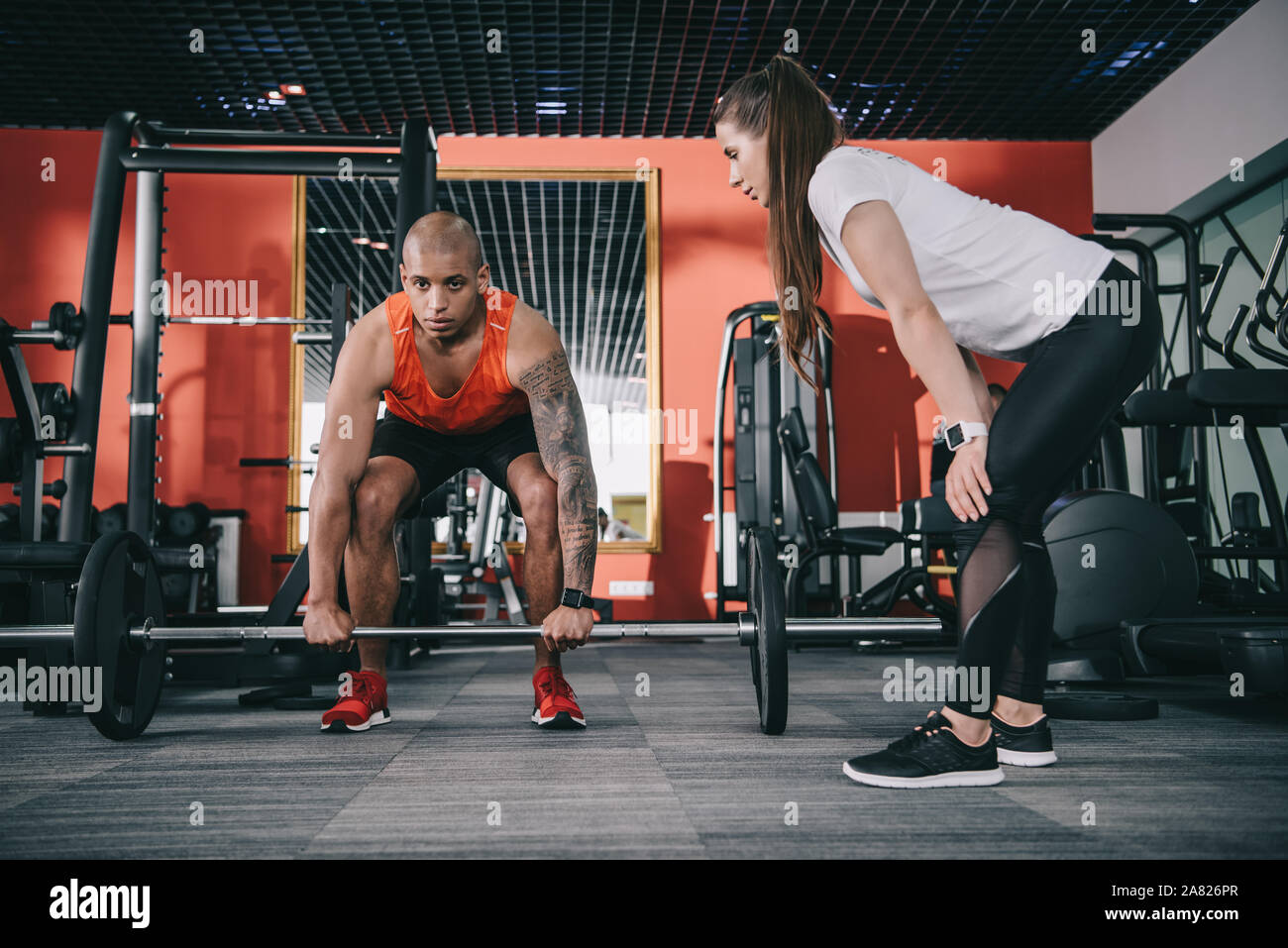 Aufmerksame trainer Überwachung der afrikanischen amerikanischen Sportler anheben Barbell Stockfoto