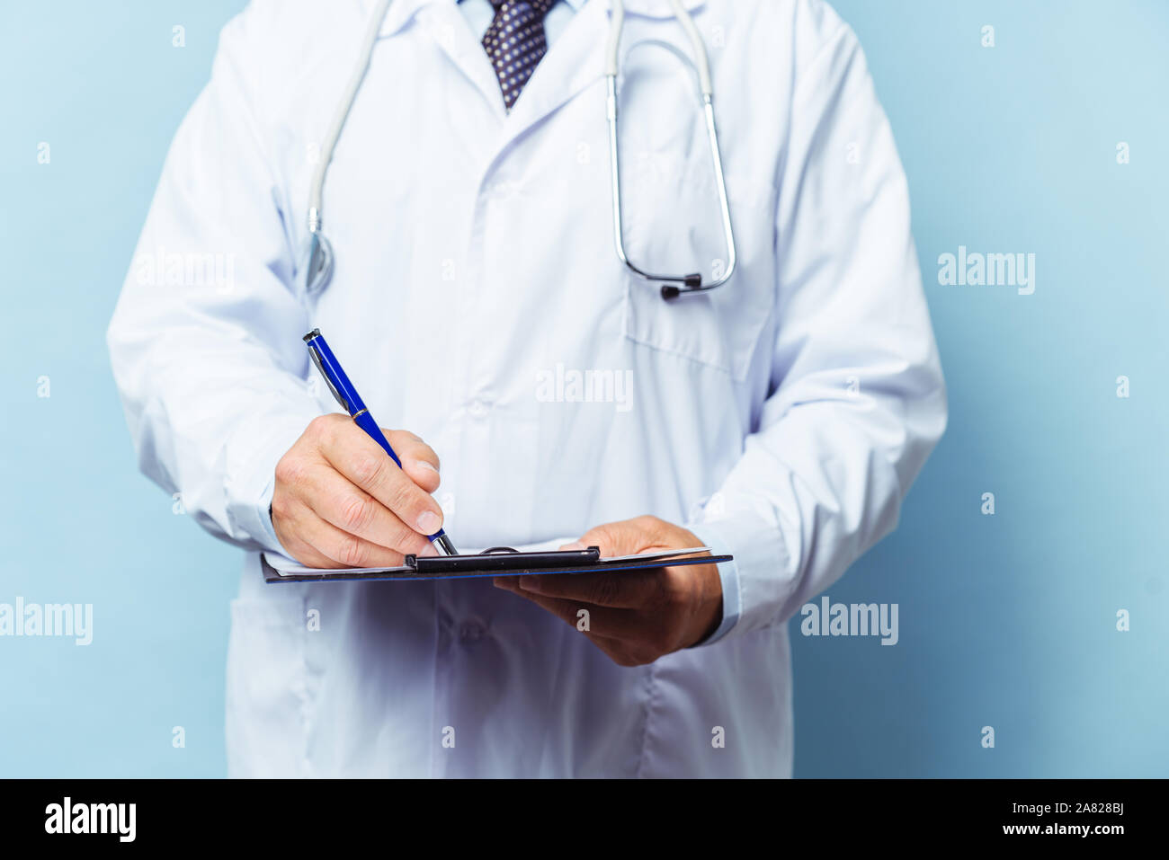 Medizinische leitender Arzt mit einem Stethoskop. Auf einem blauen Hintergrund. Der Arzt hält die Ordner in der Hand und macht einen Termin in der Klinik. Diseas Stockfoto