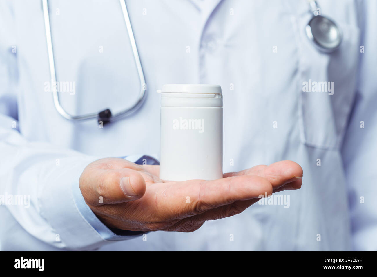 Arzt holding Flasche Pillen auf weißem Hintergrund. Das Konzept von Medizin, Pharmakologie, Gesundheitswesen. Stockfoto
