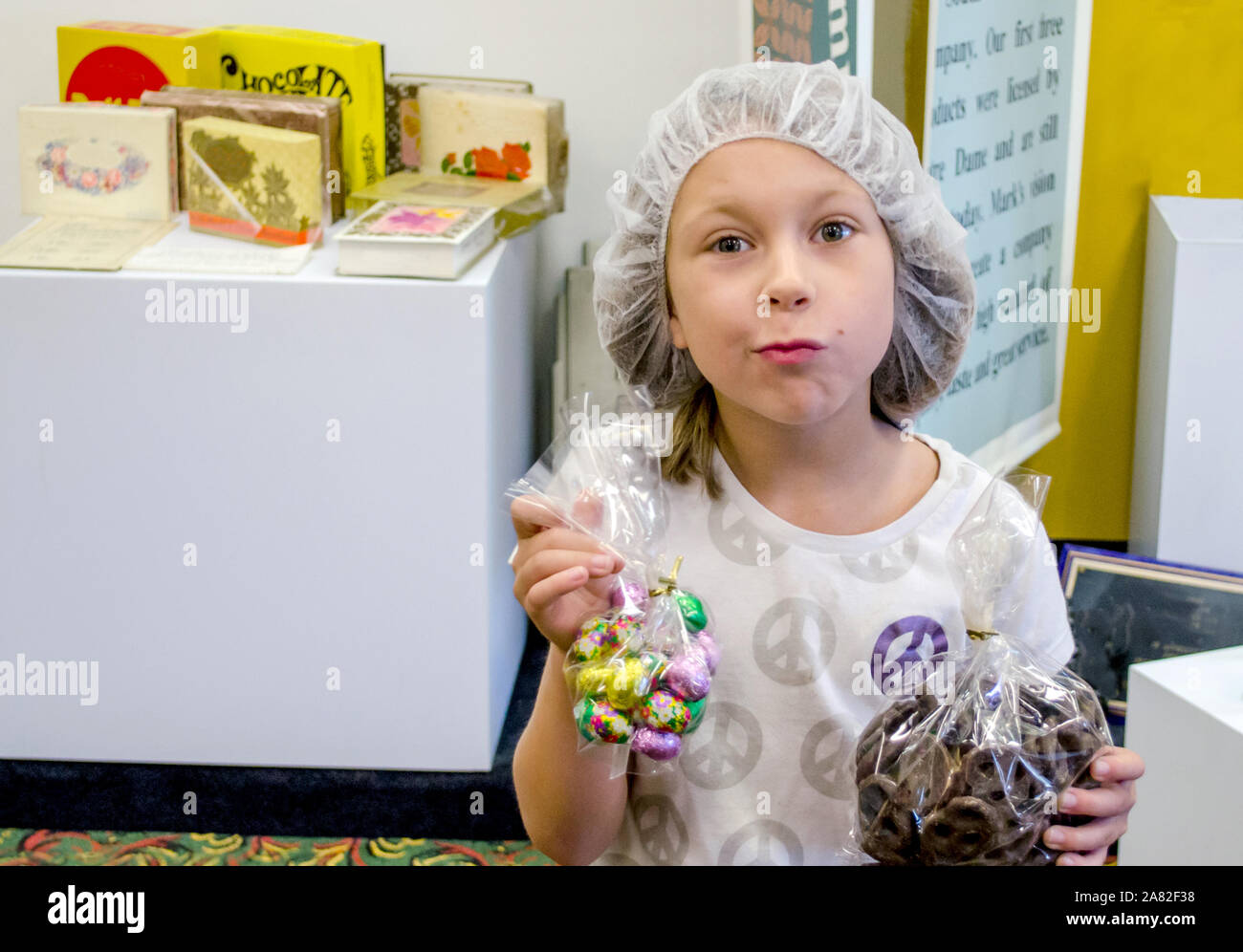 Kind mit Haarnetz an einem Candy Factory Tour, hält Tüten mit Süßigkeiten Stockfoto