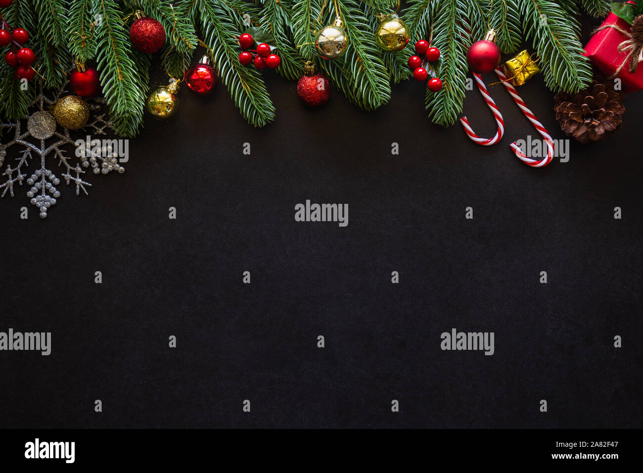 Urlaub Weihnachten Karte Hintergrund mit festlichen Dekoration Kugel, Sterne, Schneeflocken, Geschenkbox, Tannenzapfen auf schwarzem Hintergrund von Flach, Ansicht von oben. Stockfoto