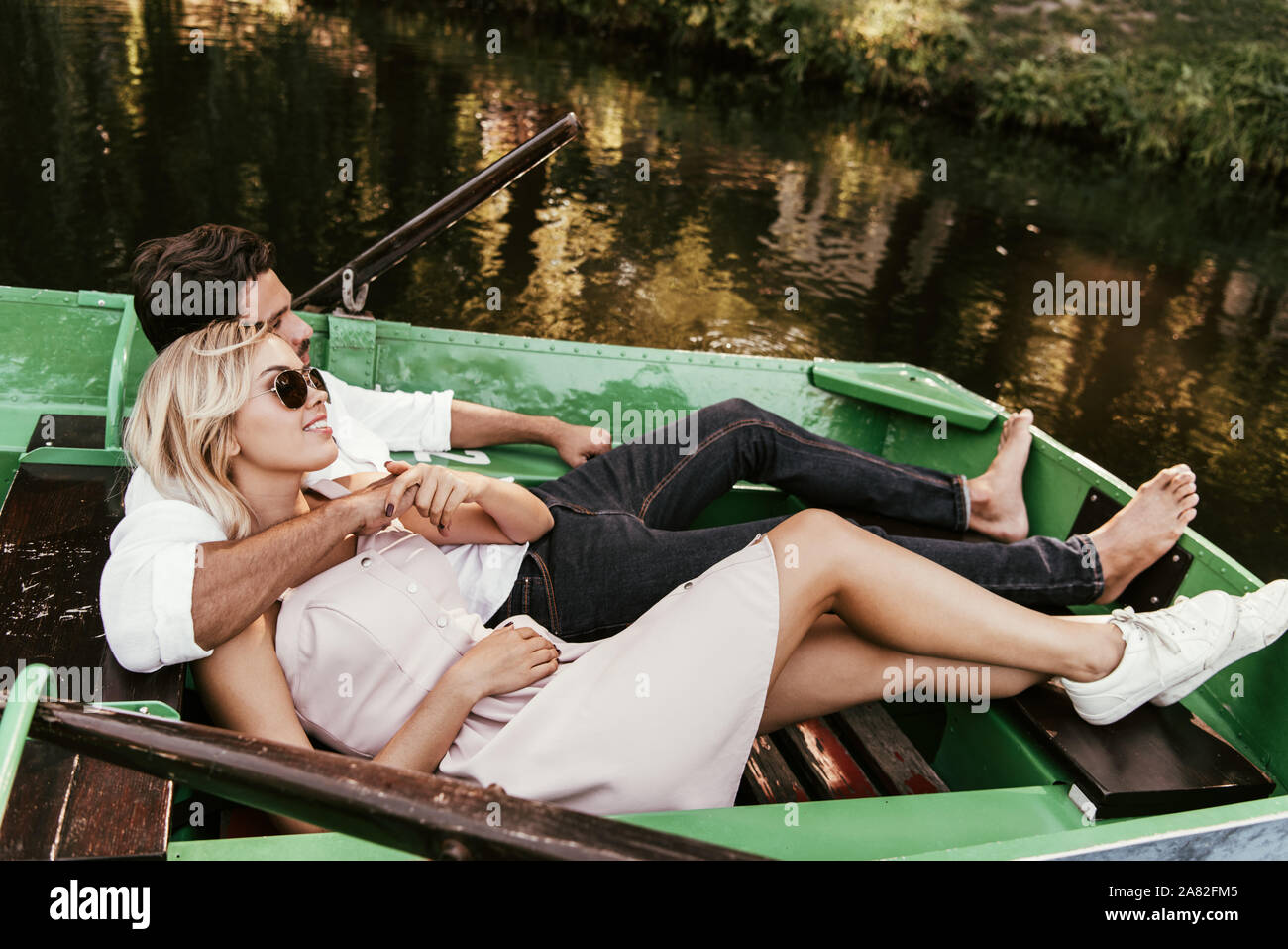 Glückliches junges Paar entspannend, während im Boot liegen auf See Stockfoto