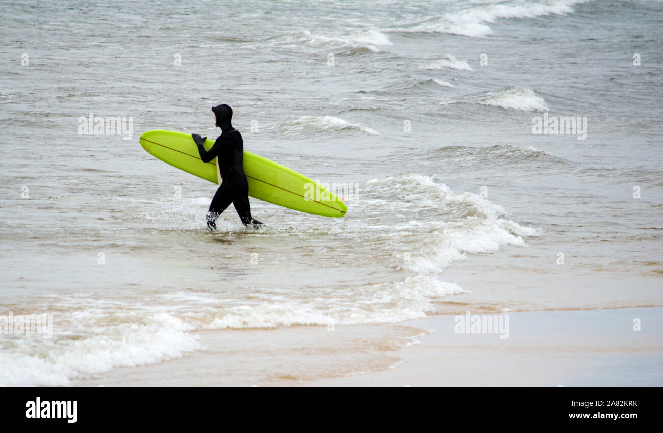 Ein Surfer zieht einen Taucheranzug kalt Wasser im See, tapfer zu Michigan Stockfoto