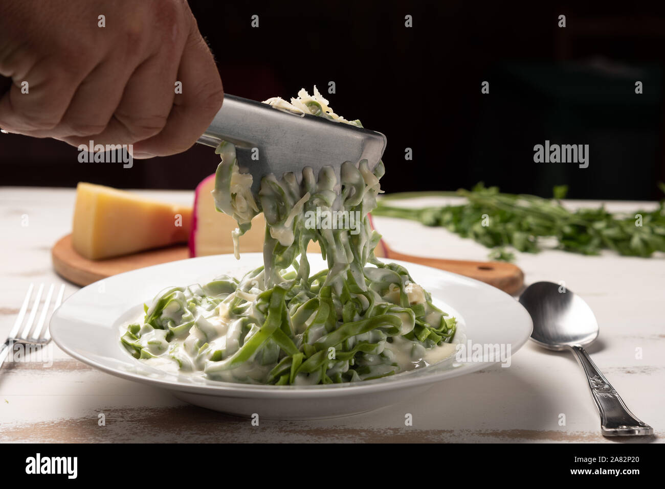 Hausgemachte greeen Spinat Bandnudeln mit béchamelsoße Soße in eine weiße Platte, rustikalen Holztisch Hintergrund, weiches Licht. Italienisches Essen Stil Stockfoto