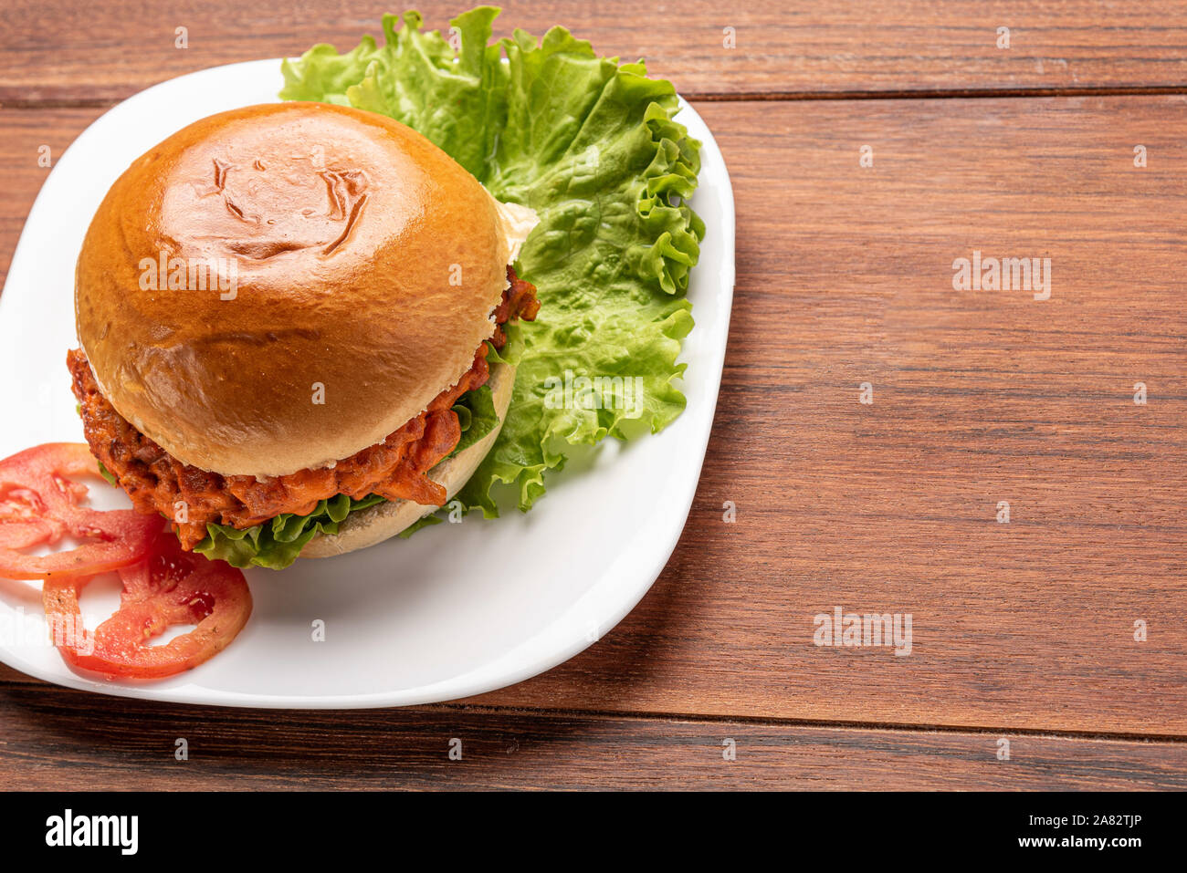 Selbstgemachte Cheeseburger mit Salat und Tomaten in einer weißen Platte auf Holz- Hintergrund Stockfoto