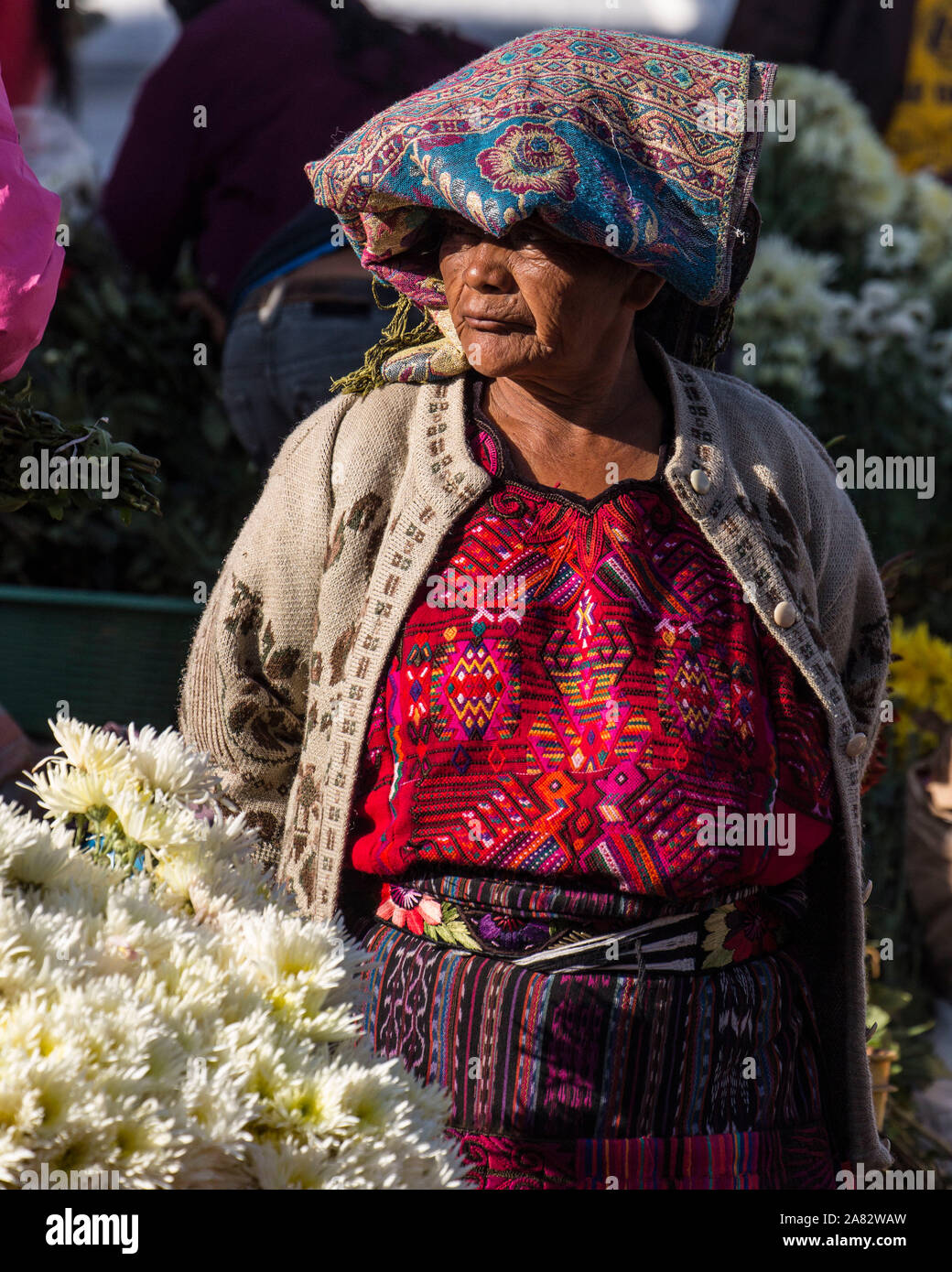 Eine Quiche Maya Frau in traditioneller Kleidung, die Blumen in der markdet auf den Stufen der Kirche von Santo Tomas in Chichicastenango, Guatemala. Stockfoto