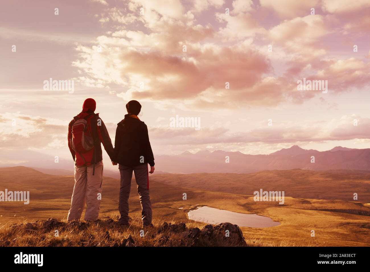 Paar Wanderer und Trekker steht gegen die Berge und den Sonnenuntergang Sonnenuntergang Stockfoto