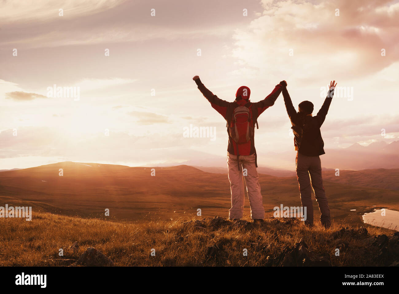 Zwei glückliche Wanderer steht mit erhobenen Armen gegen die Berge und den Sonnenuntergang Stockfoto