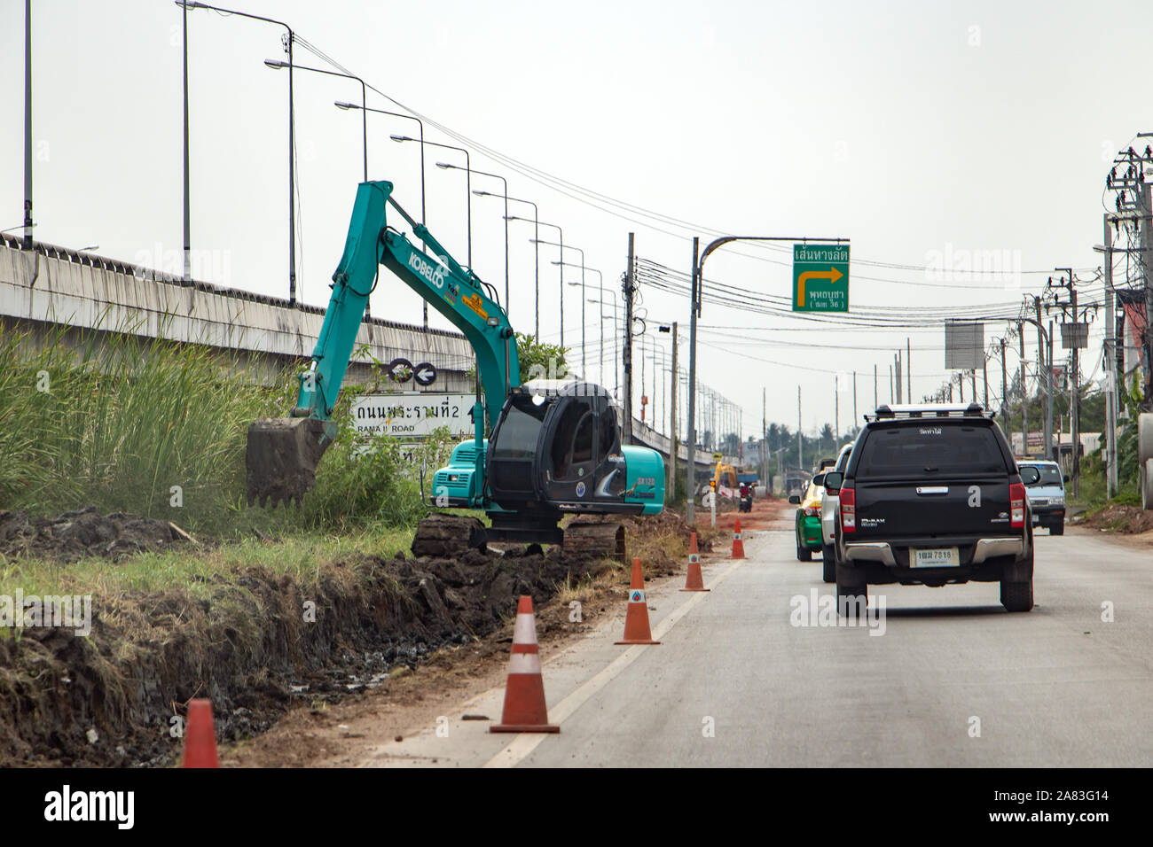 SAMUT PRAKAN, THAILAND, Apr 27 2019, Bagger neben einer Straße. Bagger gräbt Grube entlang der Fahrbahn. Stockfoto