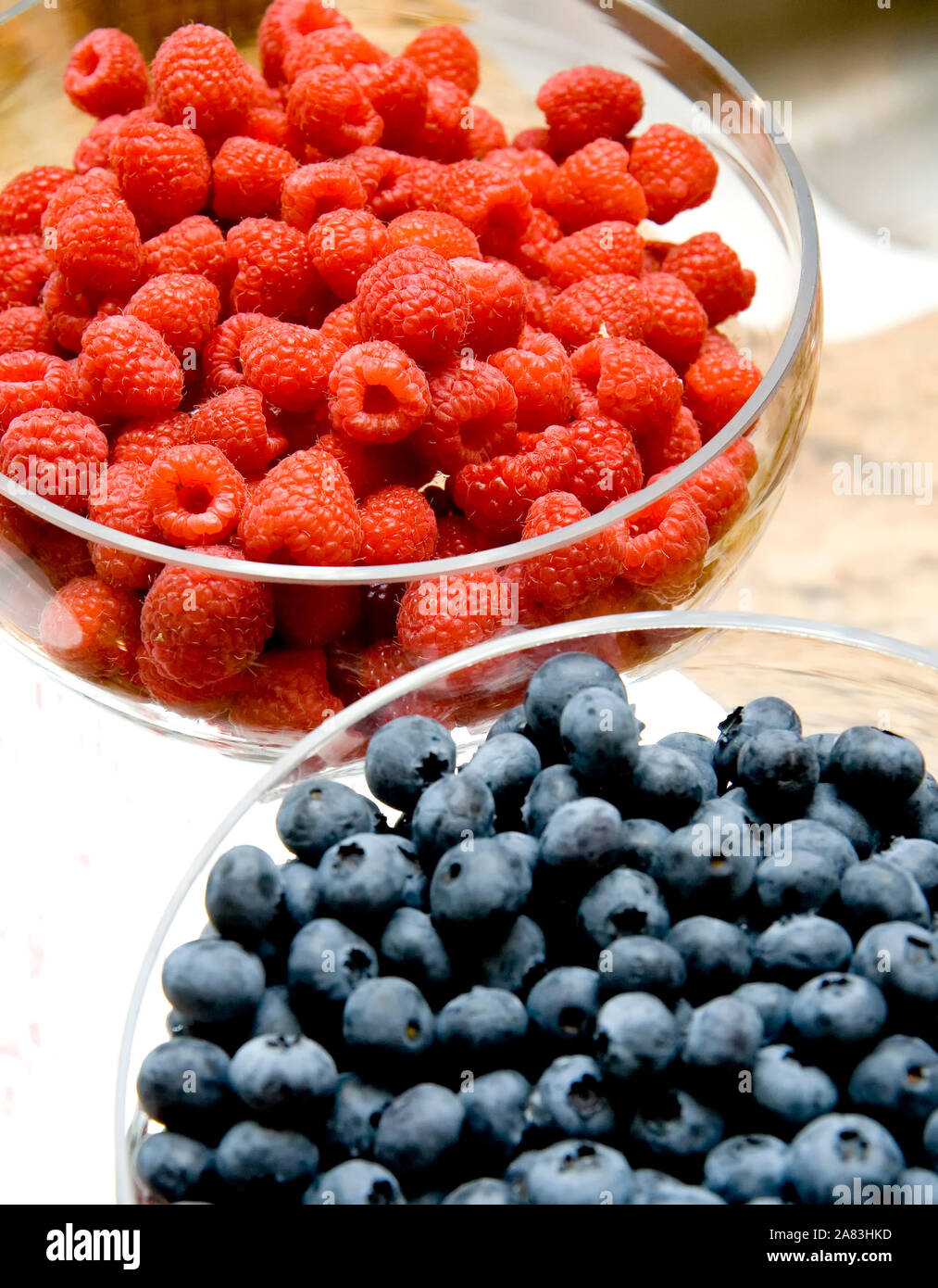 Himbeeren und Blaubeeren in Glasschalen Stockfoto