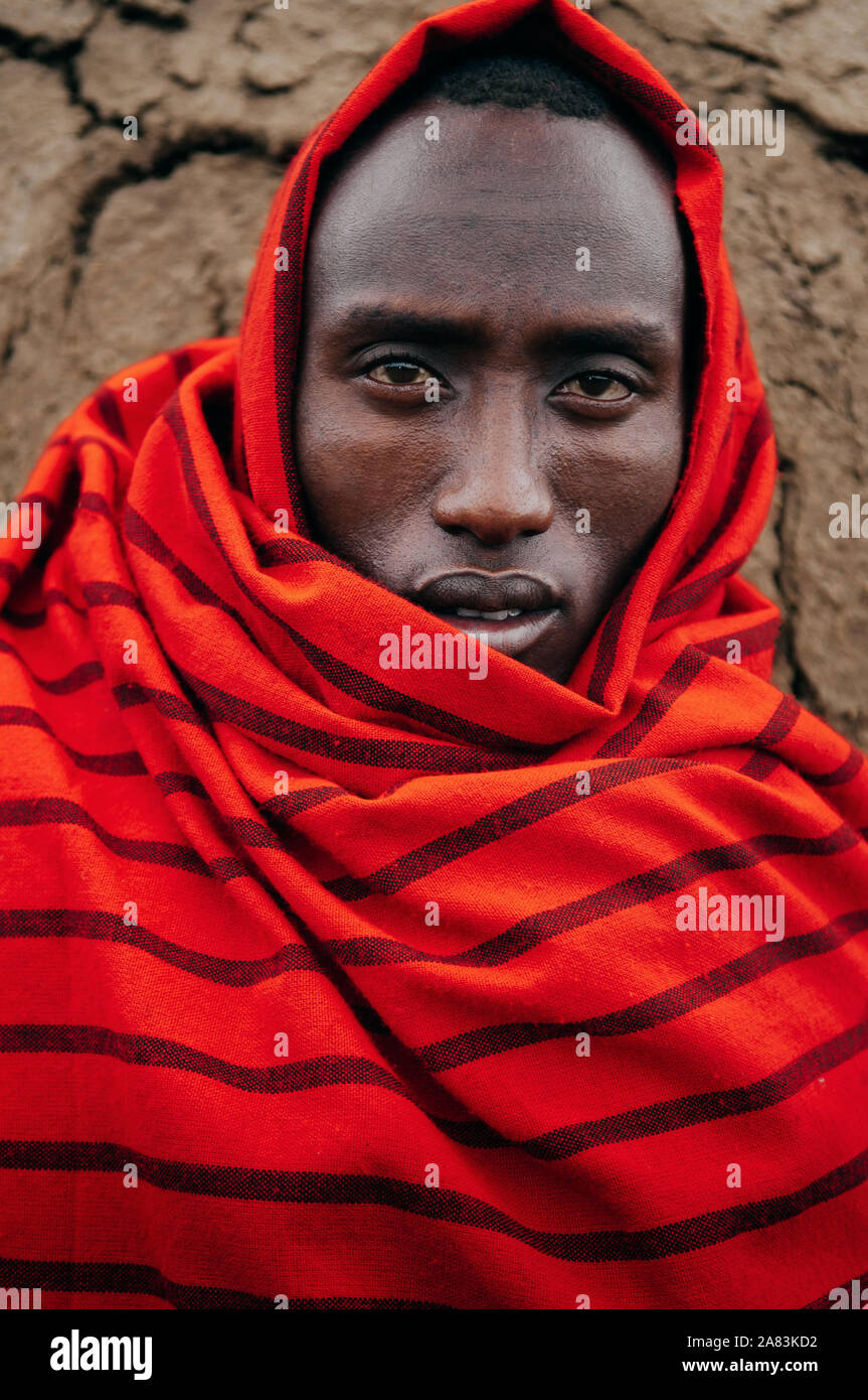 JUN 24, 2011 Serengeti, Tansania - Porträt der Afrikanischen Masai oder Masai Stamm Mann im roten Tuch Augen in die Kamera starrt. Klar Gesicht detail Falten und Stockfoto