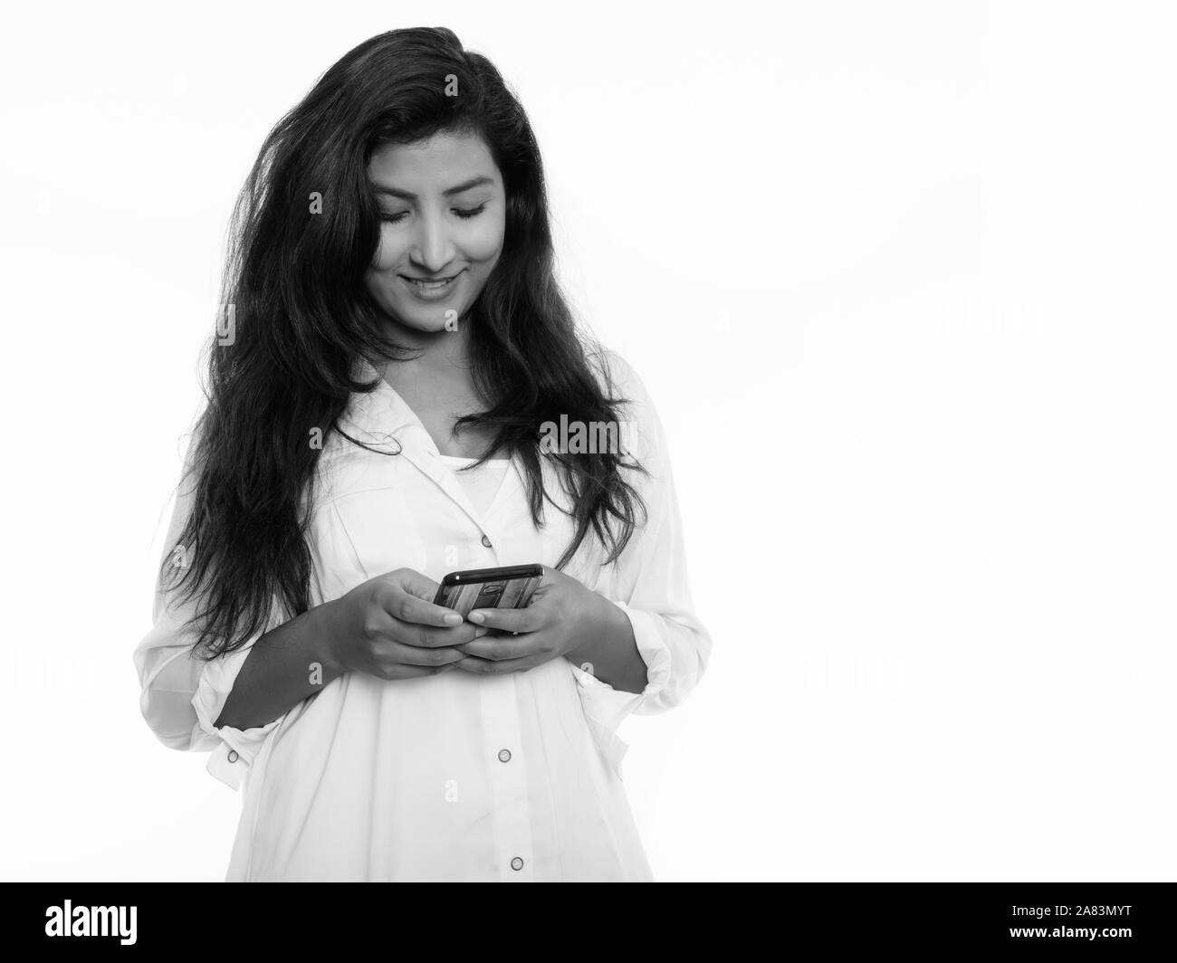 Studio shot der jungen Persischen glücklich lächelnde Frau mit Mobiltelefon Stockfoto