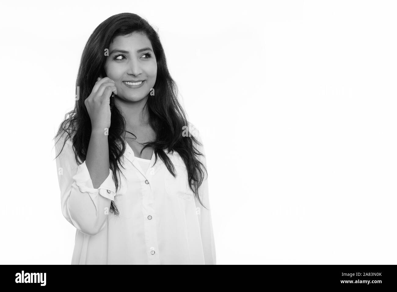 Nachdenkliche junge glücklich persische Frau lächelnd während Gespräch am Handy Stockfoto