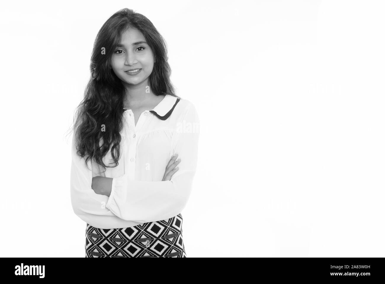 Studio shot der Jungen glücklich Persischen Geschäftsfrau lächelnd mit gekreuzten Armen Stockfoto