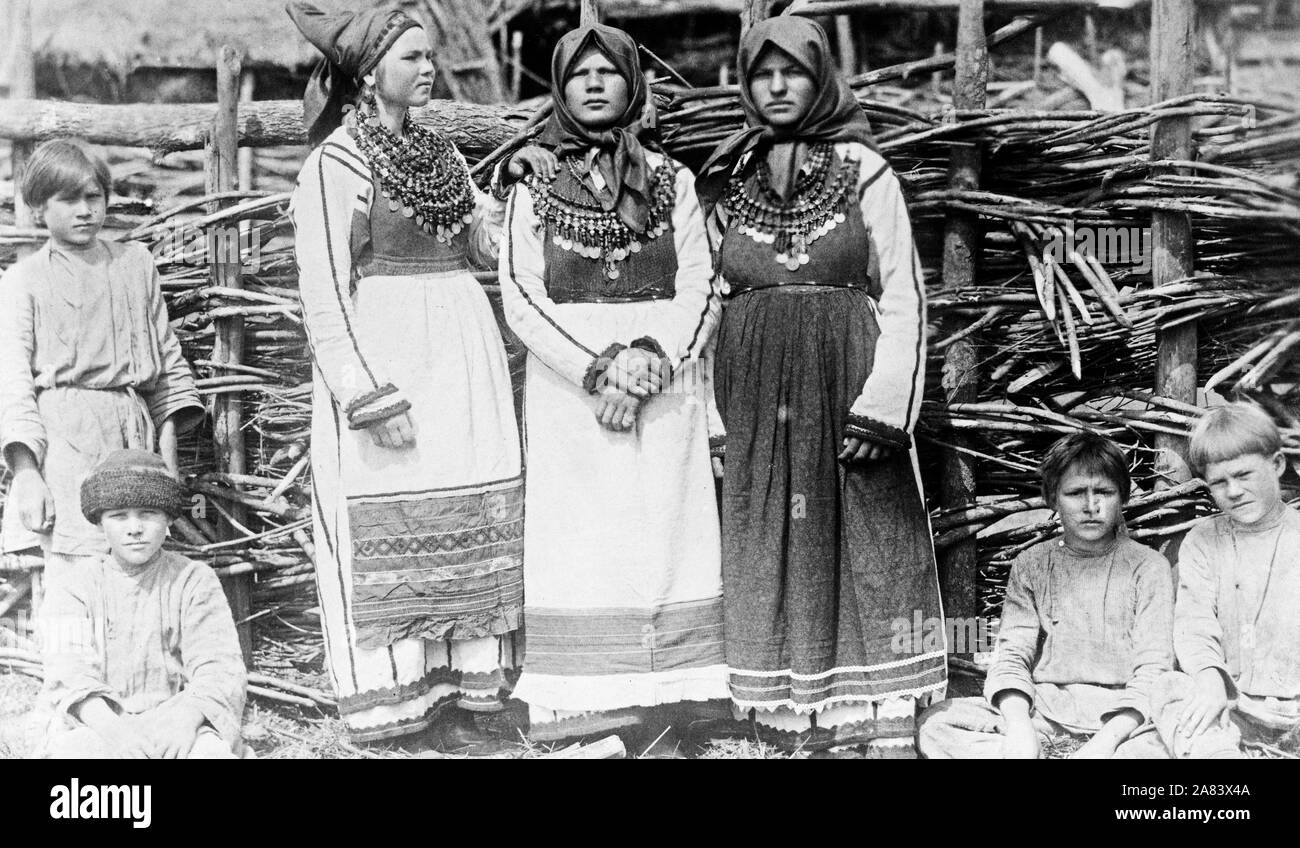 Fotos zeigen drei alte Frauen in kulturellen Kleid stand vor der Gebäude und die vier Jungs vor Zaun anmelden. Russland 1880-1924 Stockfoto