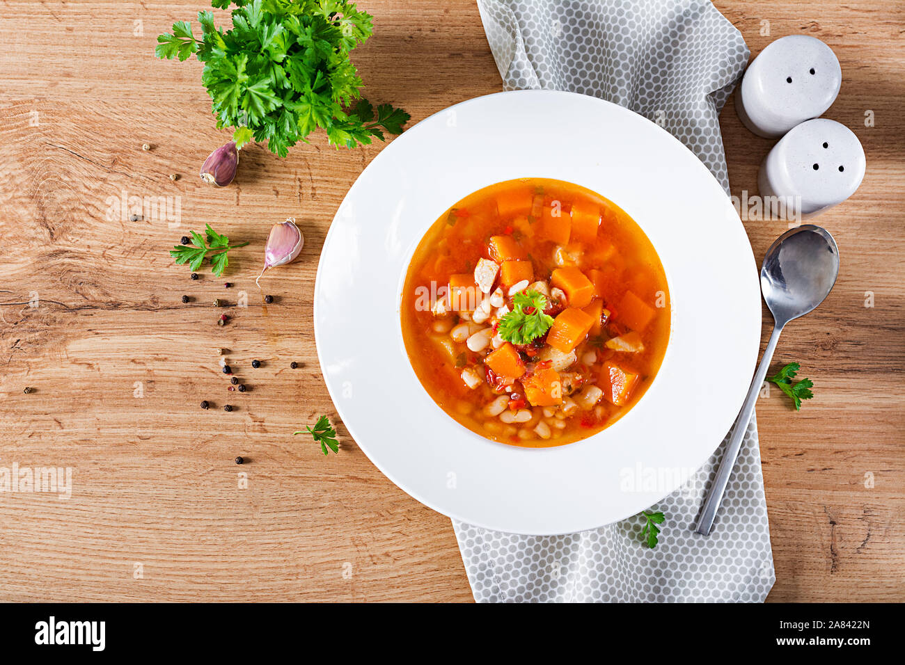 Tomate Hühnersuppe mit Kürbis und weiße Bohnen in weiße Schüssel. Ansicht von oben Stockfoto