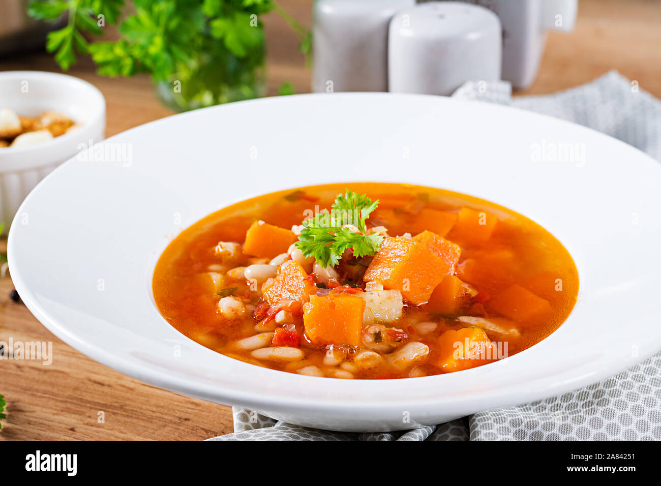 Tomate Hühnersuppe mit Kürbis und weiße Bohnen in weiße Schüssel. Stockfoto