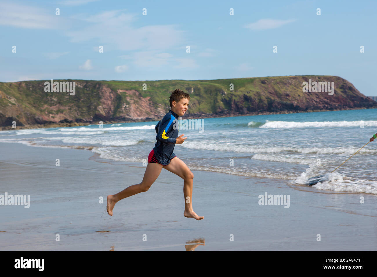 Ein kleiner Junge, der an einem leeren Strand in Großbritannien läuft. Stockfoto
