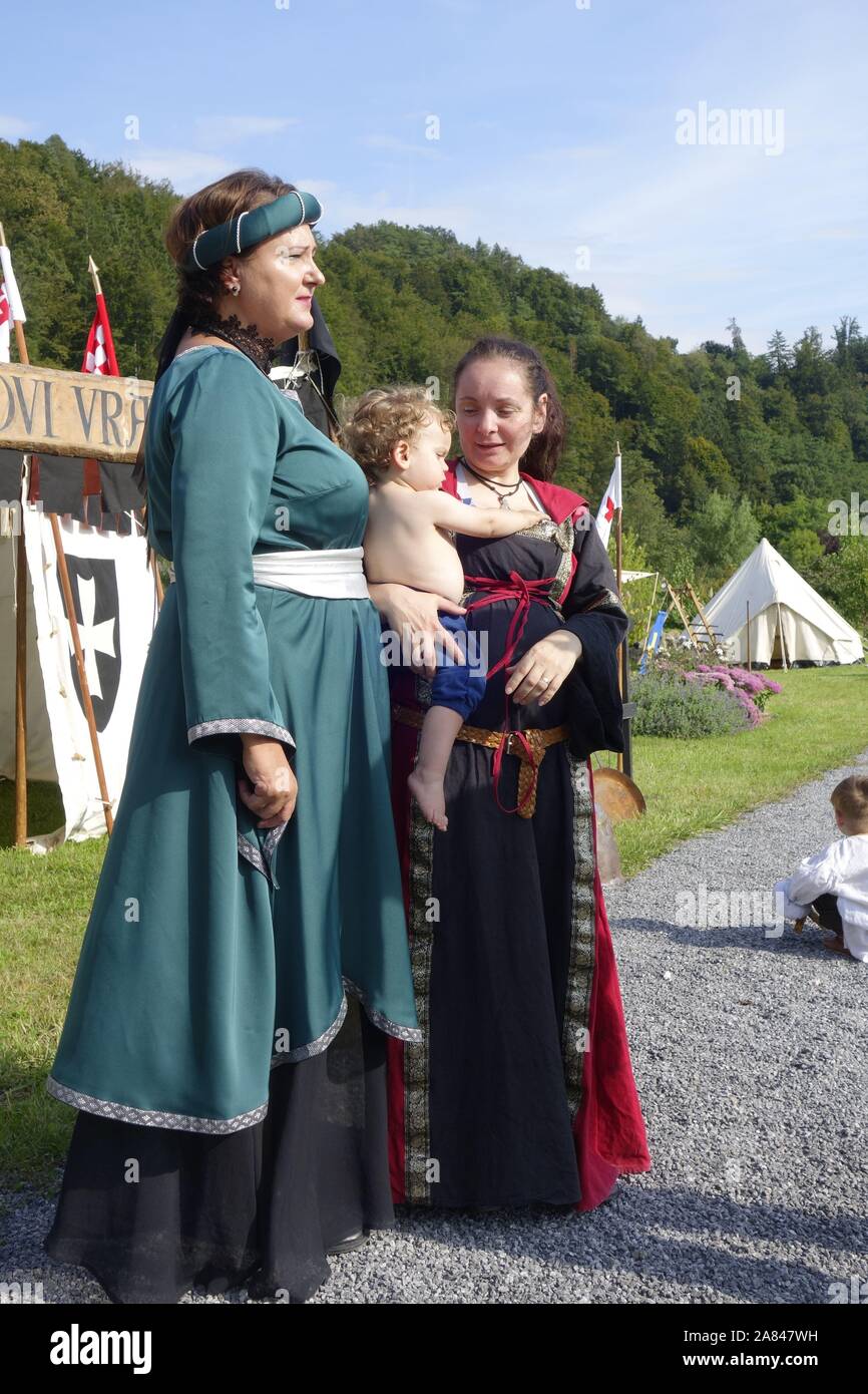 Re-enactment. Frauen in der mittelalterlichen, freie Bauern / freier Pächter, Kleider. Man hält ein Baby Kind. Tabor Mansion Hinterhof, Vojnik, Slowenien. Stockfoto
