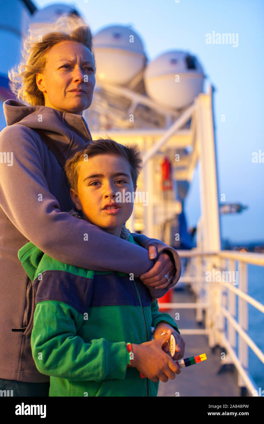 Eine Mutter umarmt ihren Sohn, während sie auf das obere Deck der Fähre, Großbritannien, blicken. Stockfoto