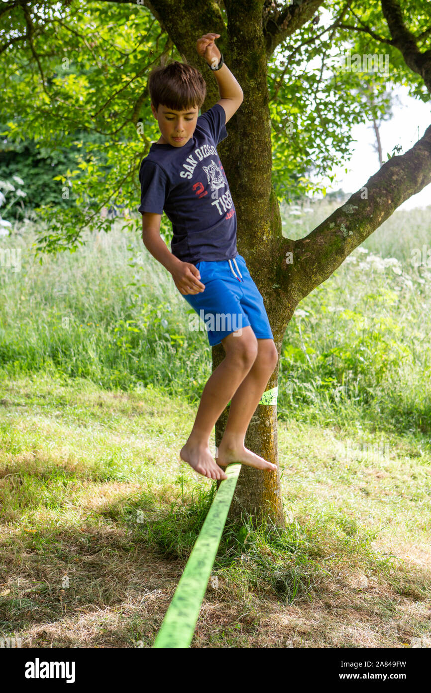 Ein Junge Spaziergänge entlang einem Durchhang - Linie zwischen zwei Bäumen gebunden, Großbritannien Stockfoto