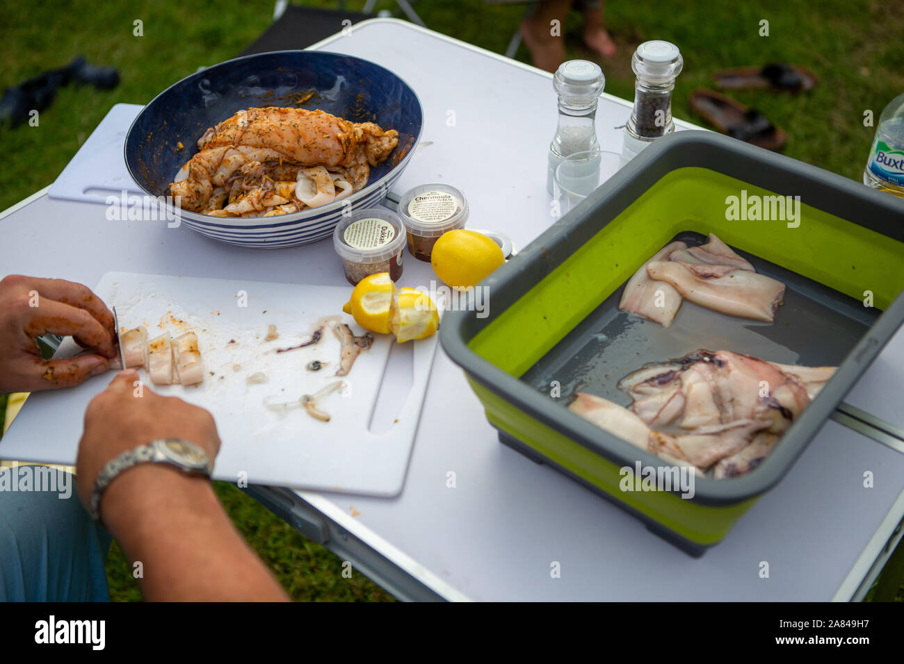 Hände schneiden frischen Tintenfisch auf, um auf dem Grill zu kochen. Stockfoto