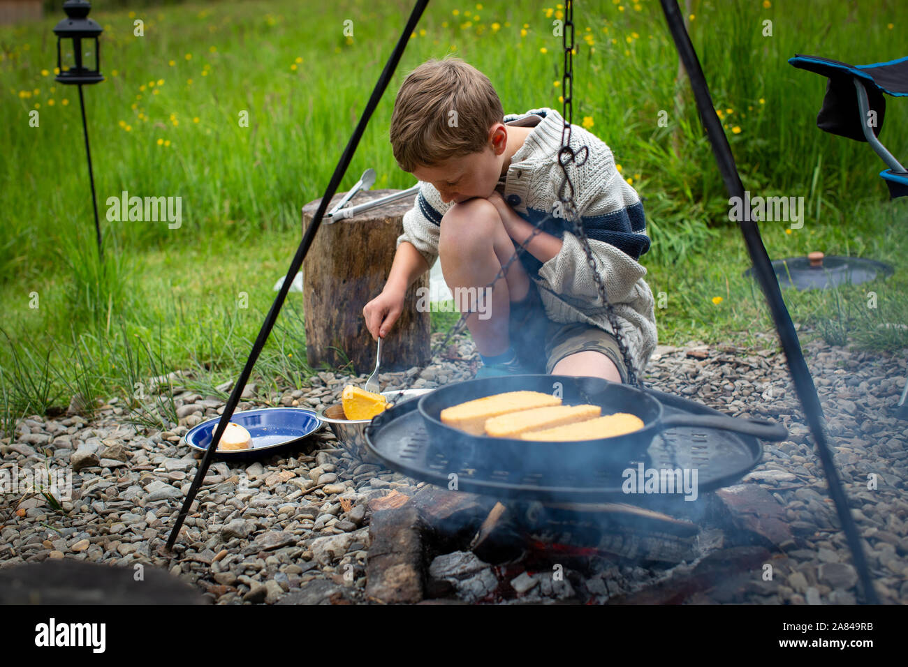 Ein junge Köche nelly Brot für das Frühstück in einer Pfanne auf einem offenen Feuer. Stockfoto