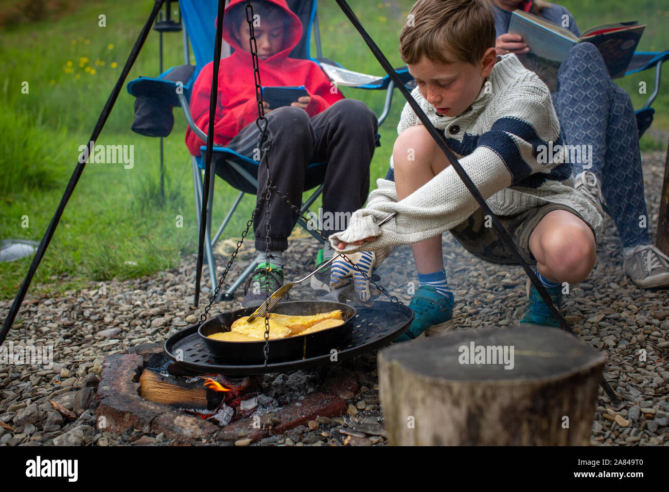 Ein junge Köche nelly Brot für das Frühstück in einer Pfanne auf einem offenen Feuer. Stockfoto