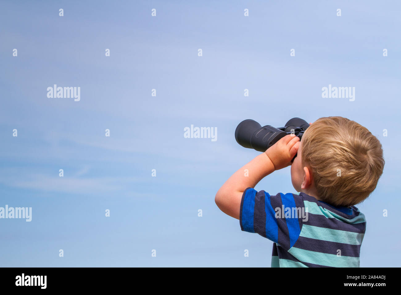 Ein Junge auf der Suche und bis an den Himmel durch ein Fernglas. Stockfoto