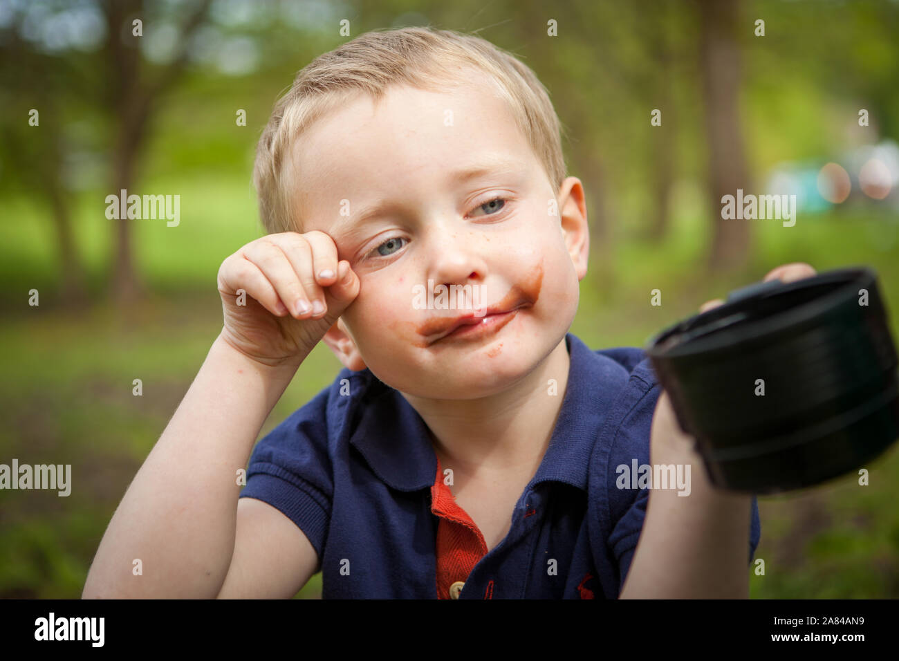 Ein Junge mit Schokolade um den Mund, während er heiße Schokolade trinkt. Stockfoto