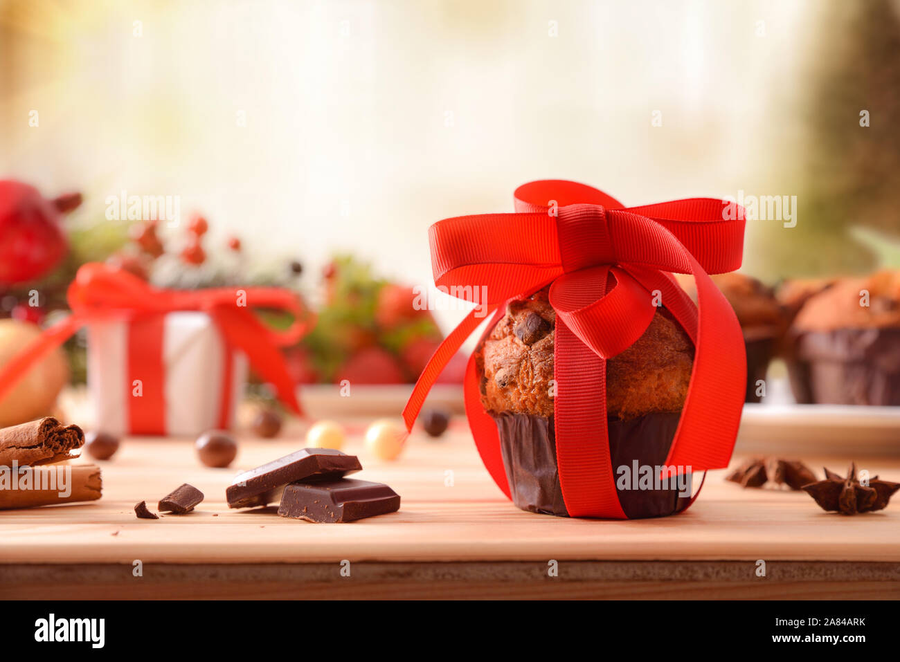 Chocolate Chip muffin auf Holztisch mit Weihnachten Objekte mit roten Schleifchen verziert. Horizontale Komposition. Vorderansicht. Stockfoto