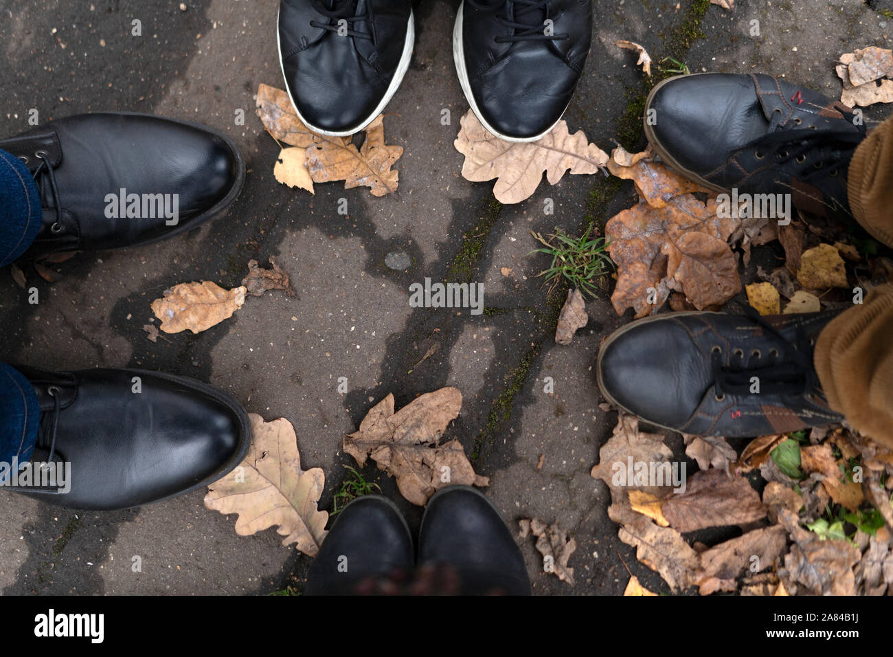 Vier Beinpaare in Stiefel und Turnschuhe auf dem Bürgersteig gegen Stockfoto