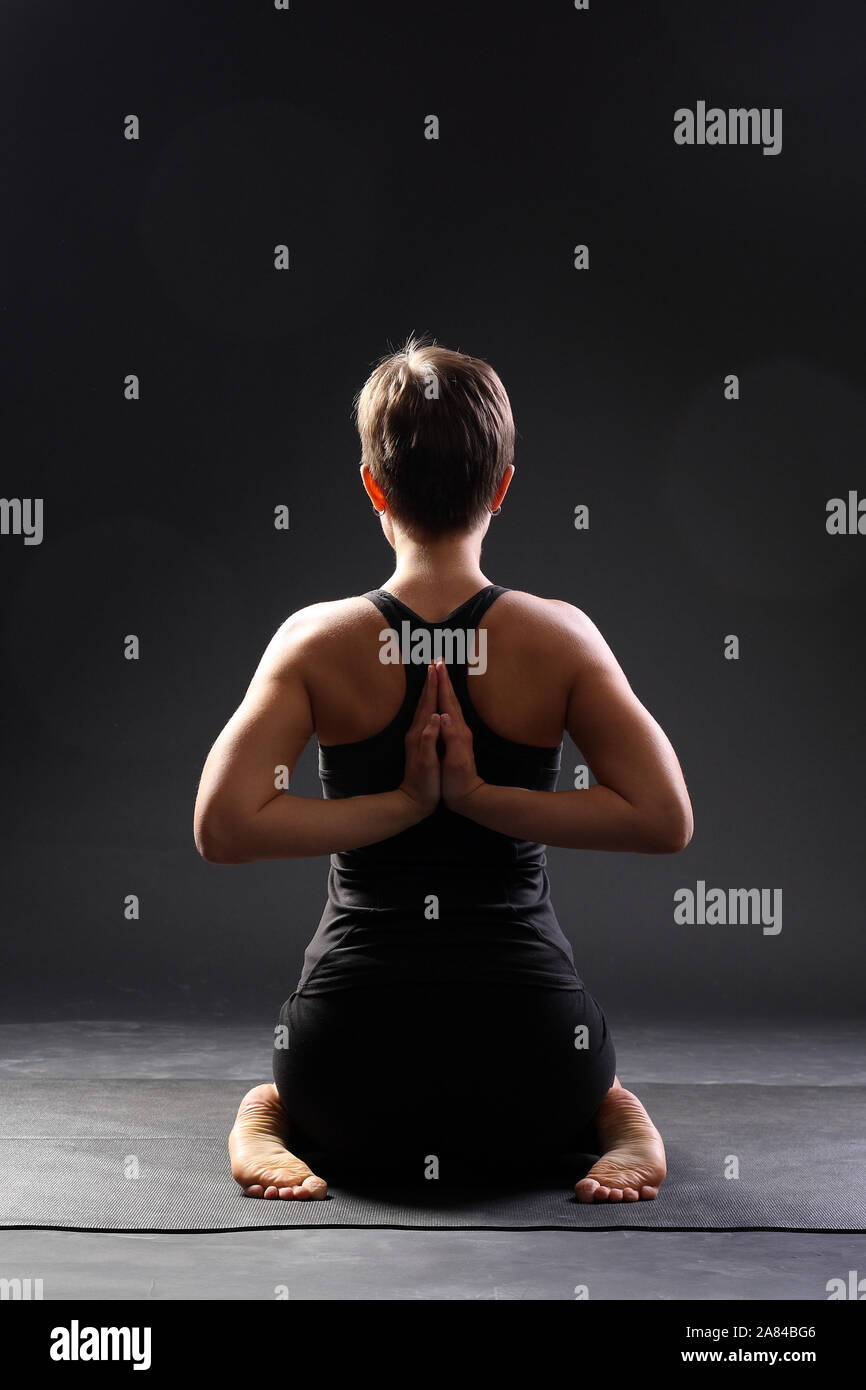 Junge Frau Yoga Übung auf der Matte in virasana oder Held Pose mit umgekehrter Gebet oder Namaste in einem Studio Stockfoto