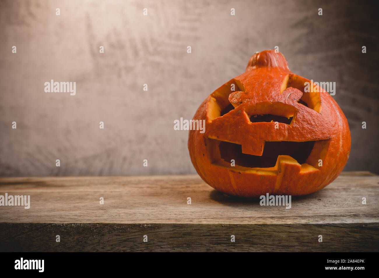Kürbis Kopf auf einem Holztisch auf dem Hintergrund einer grauen Wand mit Blätter im Herbst Stockfoto