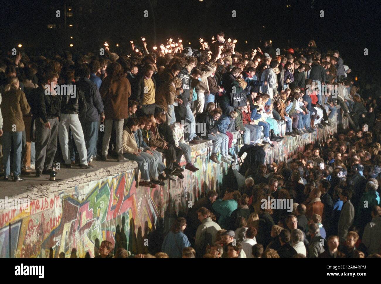 Berliner und Menschen aus ganz Deutschland feiern Sie mit Wunderkerzen auf der Berliner Mauer Am 11. November 1989. Nachdem die DDR-Führung hatte einige Grenzübergangsstellen, Millionen von Ostdeutschen in den Westen für kurze Reisen zurückgelegte geöffnet. (Dpa/IPA/Fotogramma, Berlin - 2014-10-17) ps das Foto ist verwendbar in Bezug auf den Kontext, in dem es aufgenommen wurde, und ohne beleidigende Absicht der Anstand des Volkes vertreten Redaktionelle Nutzung Stockfoto