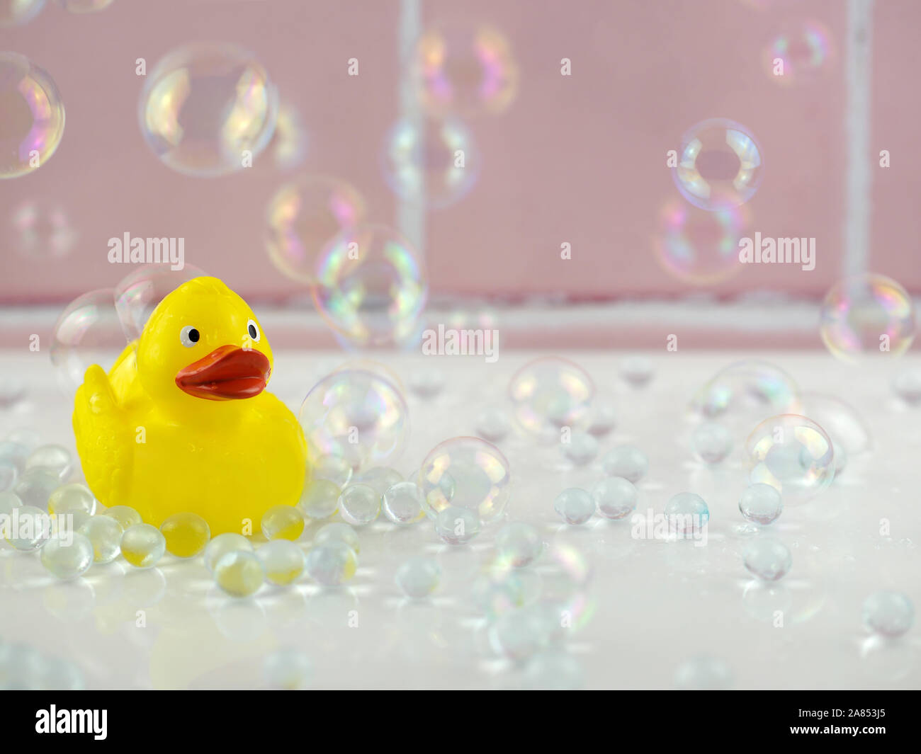 Gelbe Gummiente in Bad mit Blasen und rosa Kacheln Stockfoto